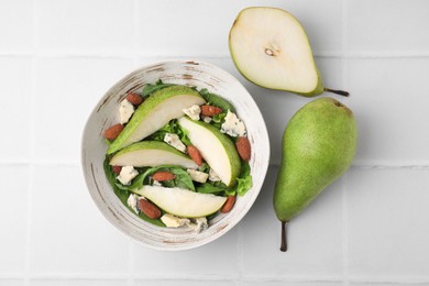 Photo of Delicious pear salad in bowl and fruits on light tiled table, top view