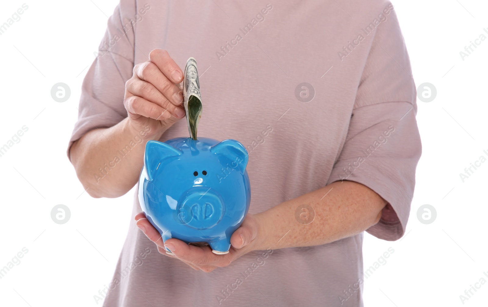 Photo of Mature woman putting money into piggy bank on white background