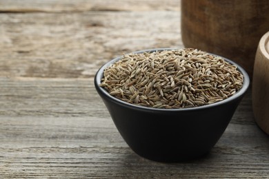 Photo of Bowl of caraway seeds on wooden table, closeup. Space for text