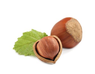 Photo of Tasty organic hazelnuts and leaf on white background