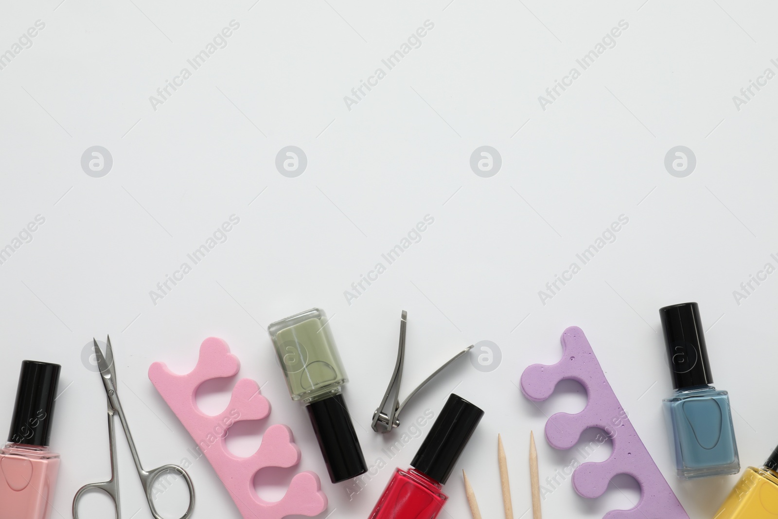 Photo of Nail polishes and set of pedicure tools on white background, flat lay. Space for text