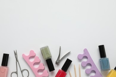 Photo of Nail polishes and set of pedicure tools on white background, flat lay. Space for text