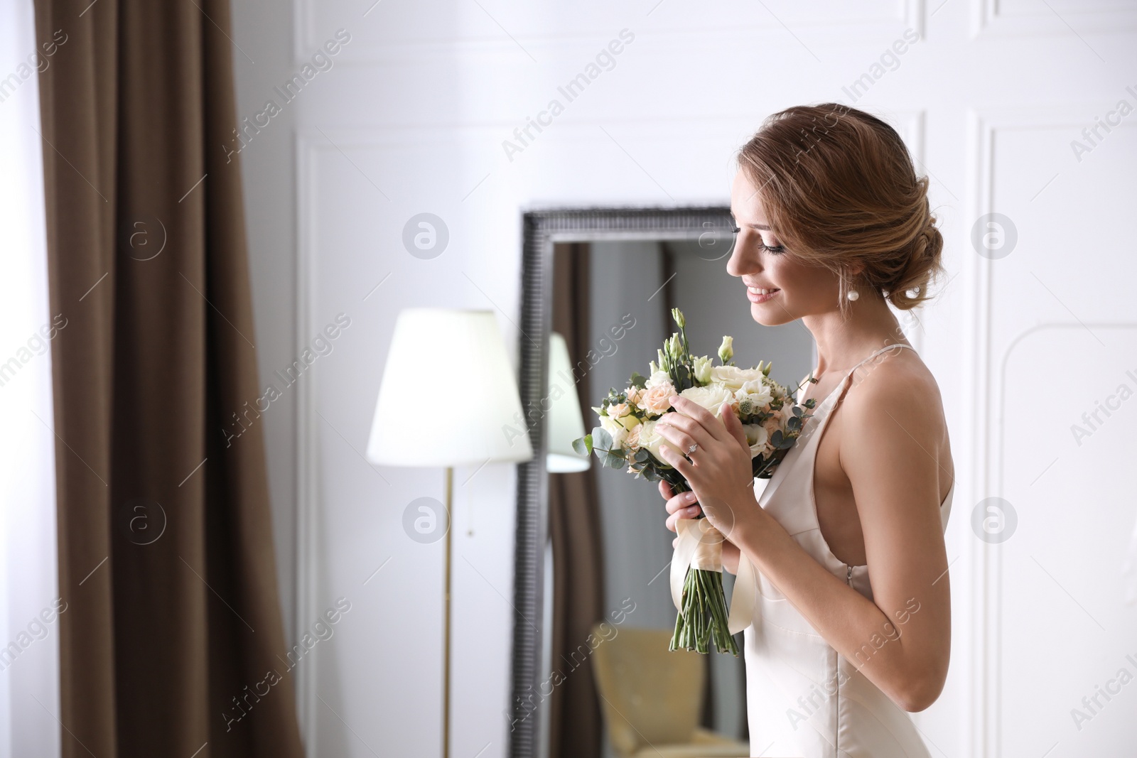 Photo of Bride in beautiful wedding dress with bouquet indoors