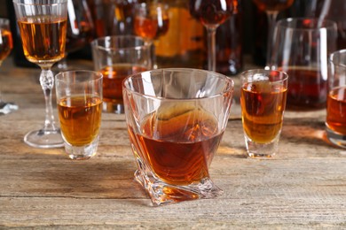 Different delicious liqueurs in glasses on wooden table