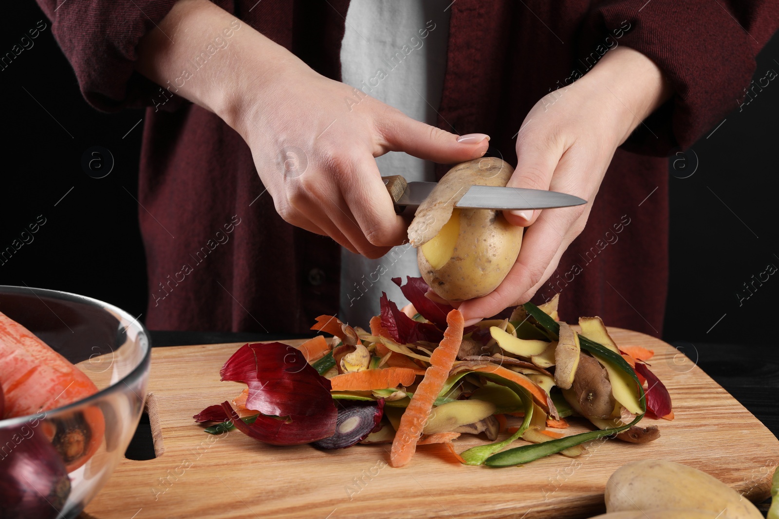 Photo of Woman peeling fresh potato with knife at table, closeup