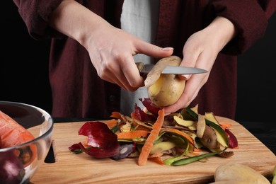 Photo of Woman peeling fresh potato with knife at table, closeup