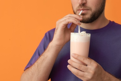 Photo of Young man with glass of delicious milk shake on color background