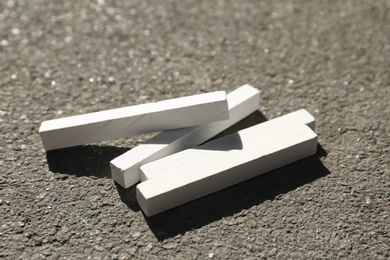 Many white chalk sticks on asphalt, closeup