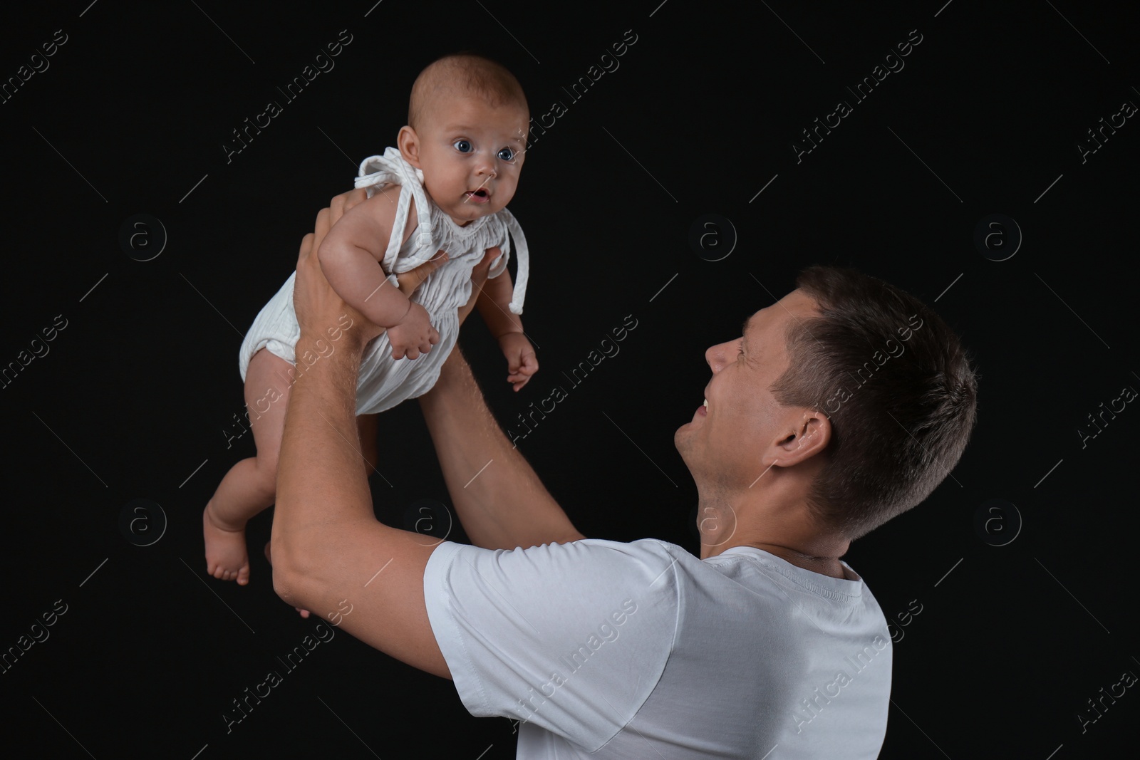 Photo of Happy father with his little baby on black background