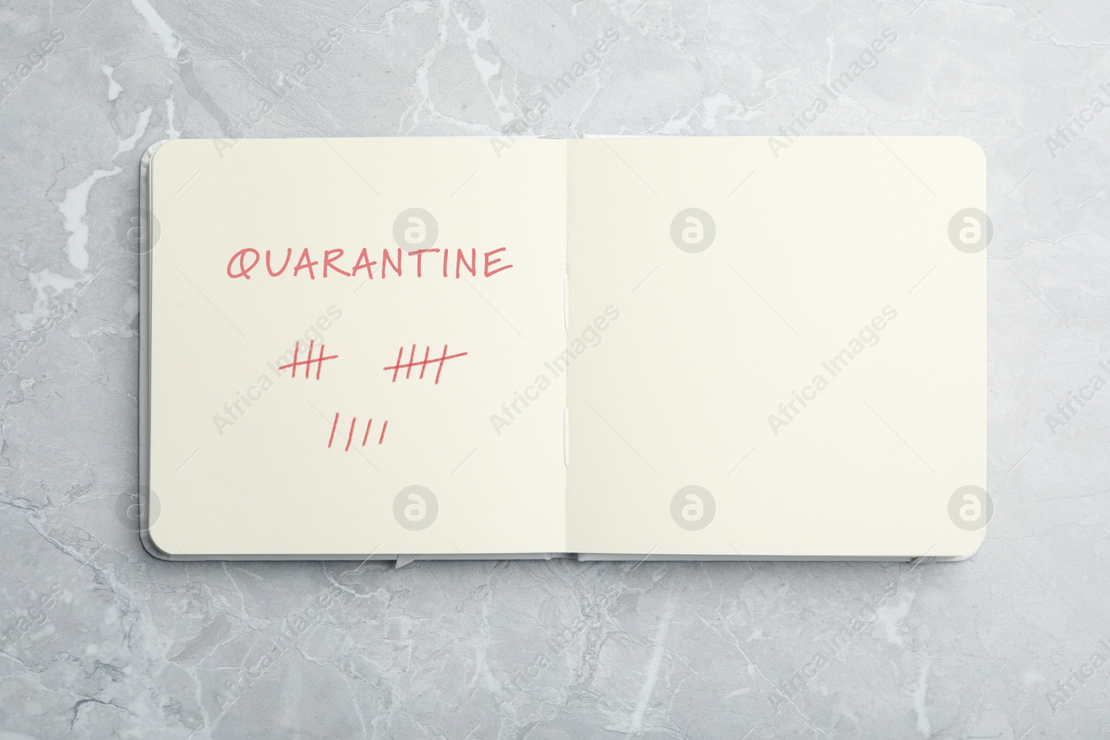 Image of Open notebook on marble table, top view. Counting days of quarantine during coronavirus outbreak 
