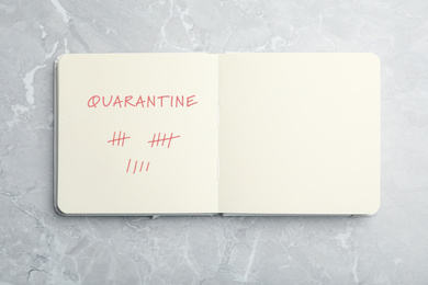 Open notebook on marble table, top view. Counting days of quarantine during coronavirus outbreak 