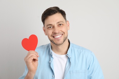 Photo of Portrait of man with paper heart on light background