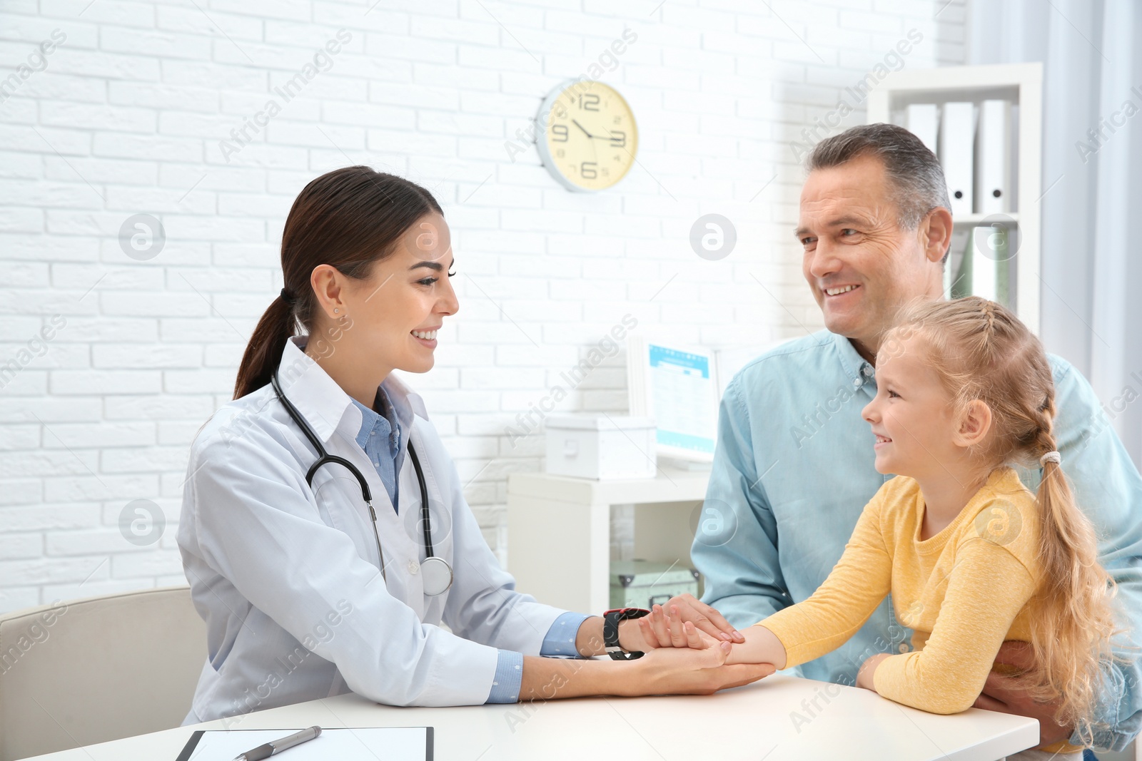 Photo of Mature man with granddaughter visiting doctor in hospital. Checking pulse