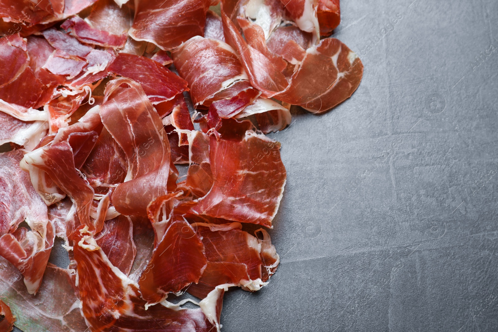 Photo of Tasty prosciutto on grey table, flat lay. Space for text