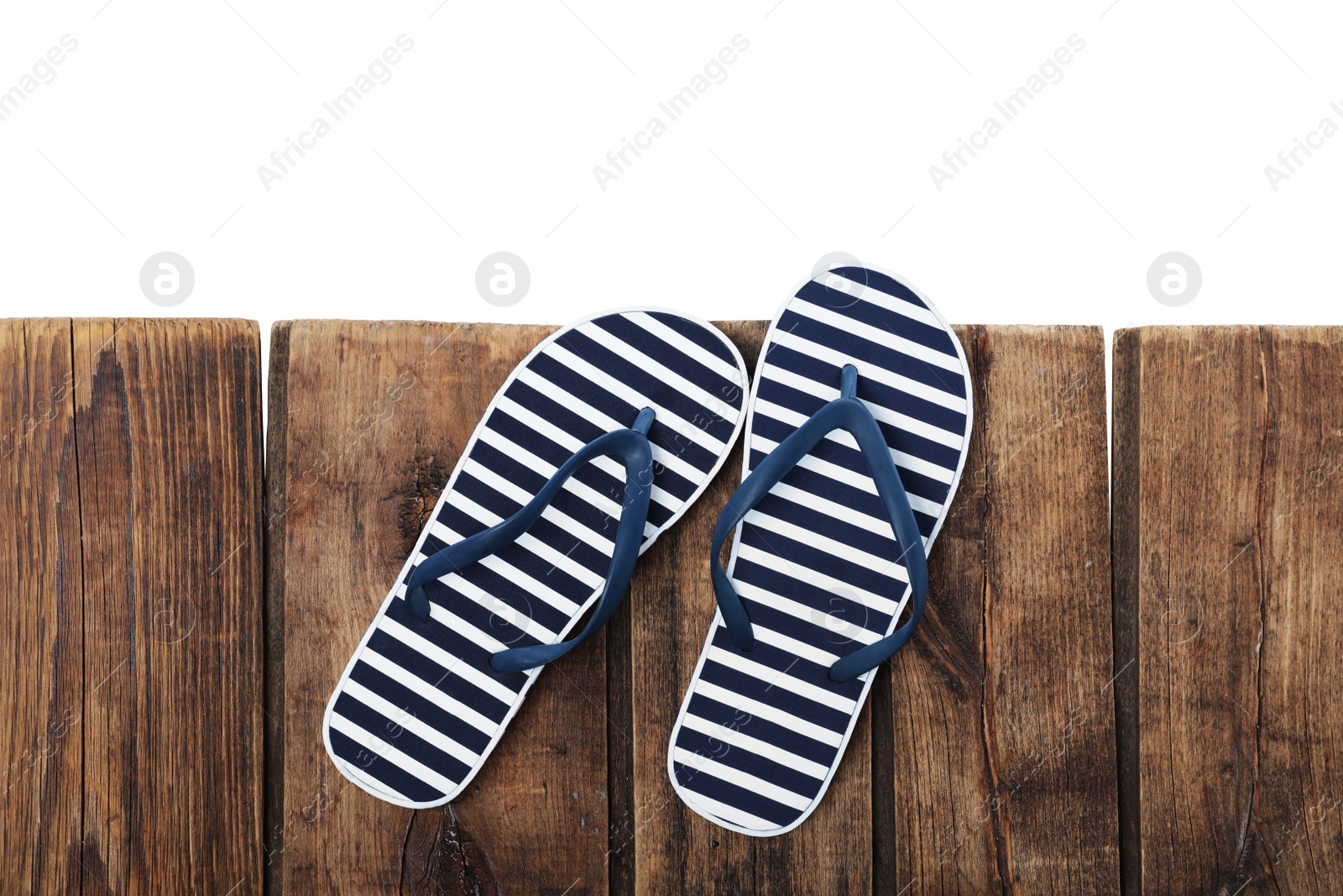 Photo of Striped flip flops on wooden table against white background, top view