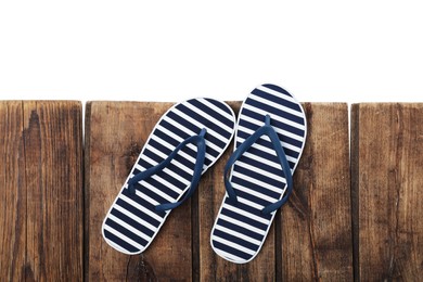 Photo of Striped flip flops on wooden table against white background, top view