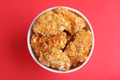 Photo of Bucket with yummy nuggets on pink background, top view