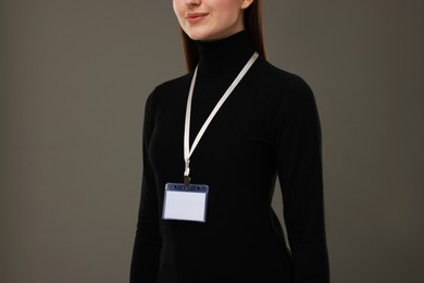 Woman with blank badge on grey background, closeup