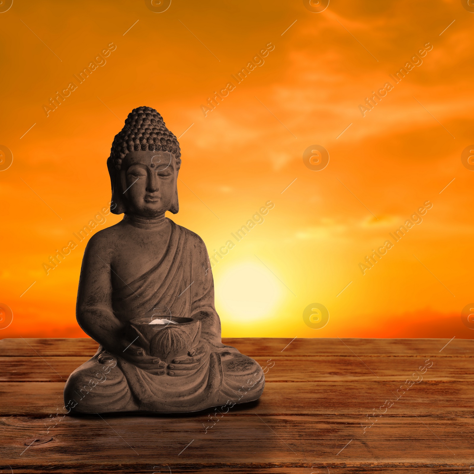 Image of Beautiful stone Buddha sculpture on wooden surface at sunset. Space for text