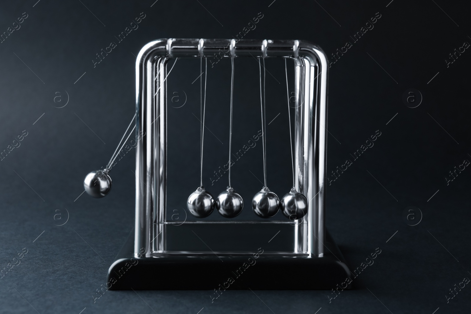 Photo of Newton's cradle on dark background. Physics law of energy conservation