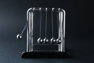 Photo of Newton's cradle on dark background. Physics law of energy conservation