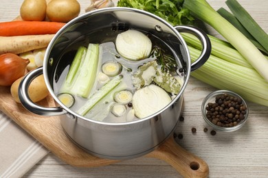 Photo of Pot and different ingredients for cooking tasty bouillon on white wooden table