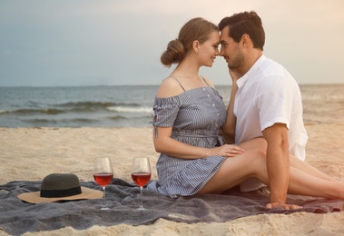 Photo of Happy young couple having picnic at sea beach