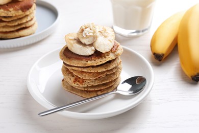 Photo of Plate of banana pancakes served on white wooden table, closeup