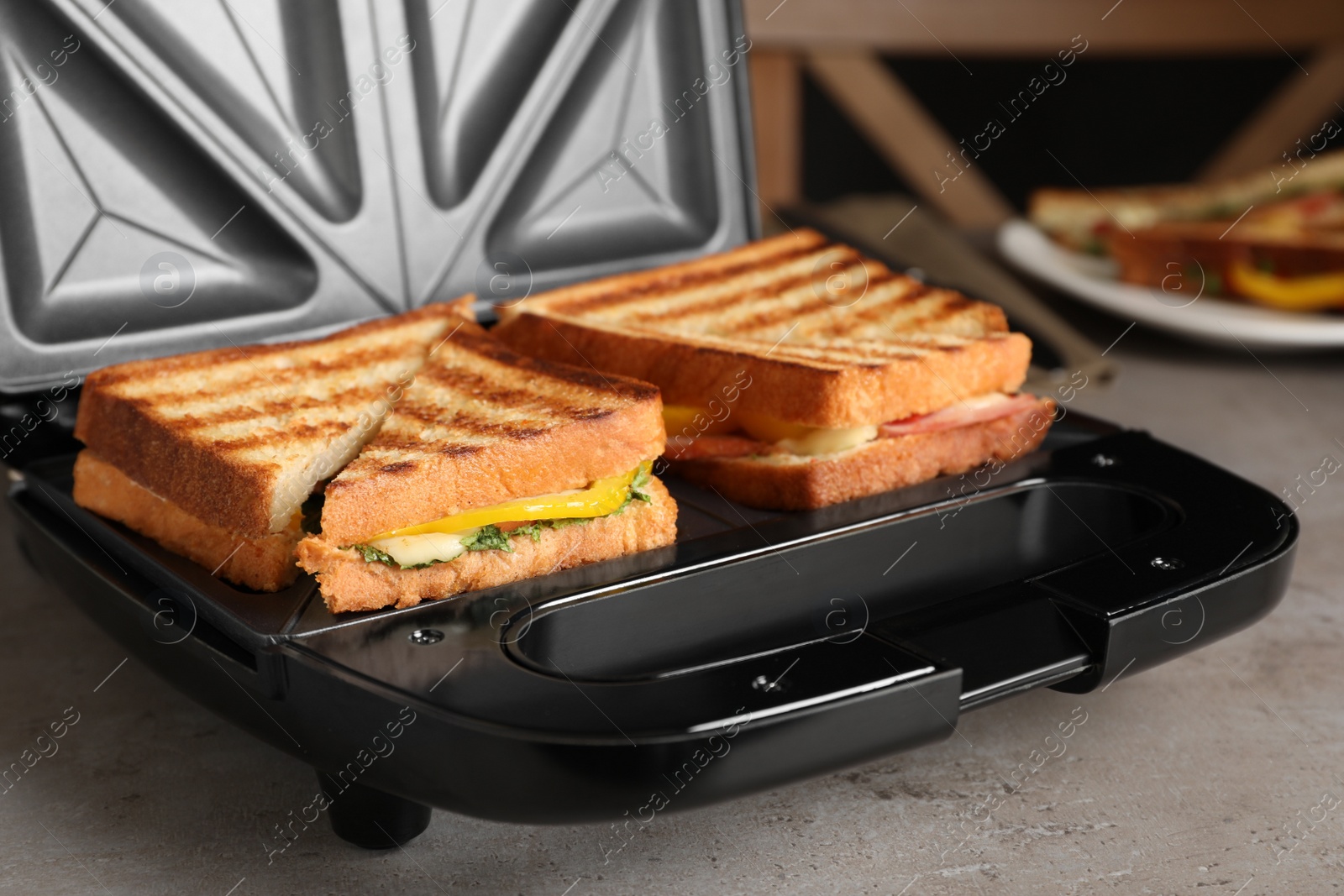 Photo of Modern grill maker with tasty sandwiches, closeup view