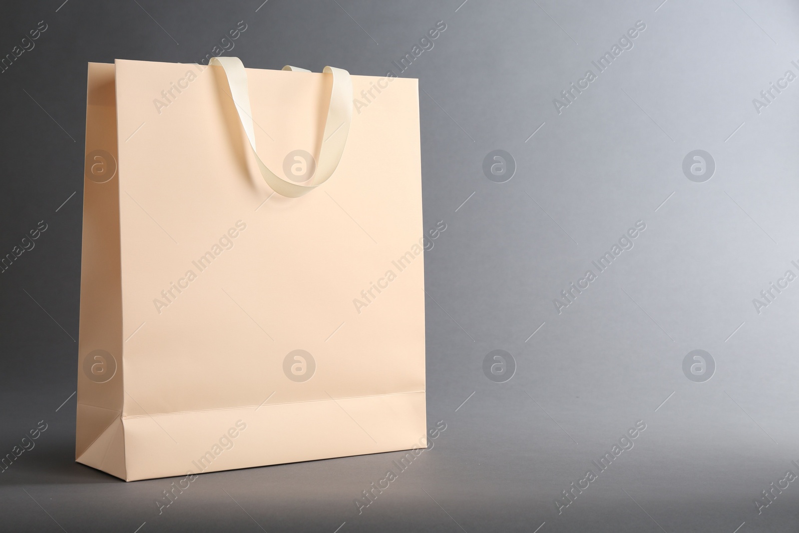 Photo of One paper bag on grey background, space for text. Mockup for design