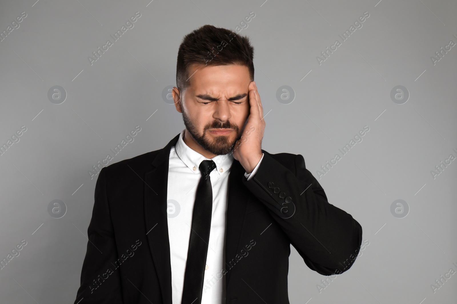 Photo of Businessman suffering from headache on light grey background