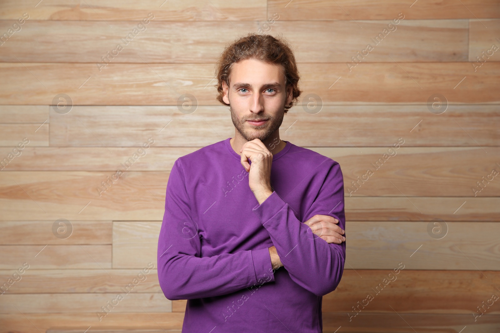 Photo of Handsome young man in warm sweater on wooden background
