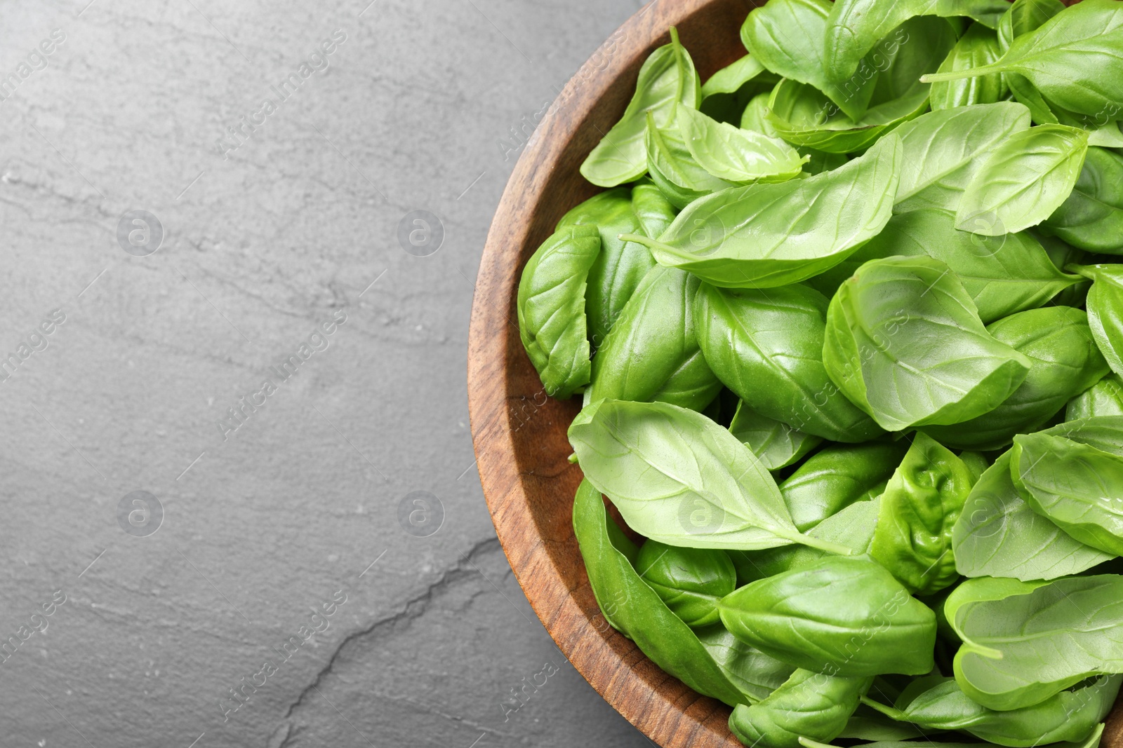 Photo of Fresh basil leaves on grey table, top view