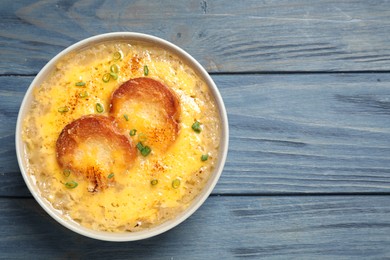 Photo of Tasty homemade french onion soup on blue wooden table, top view. Space for text