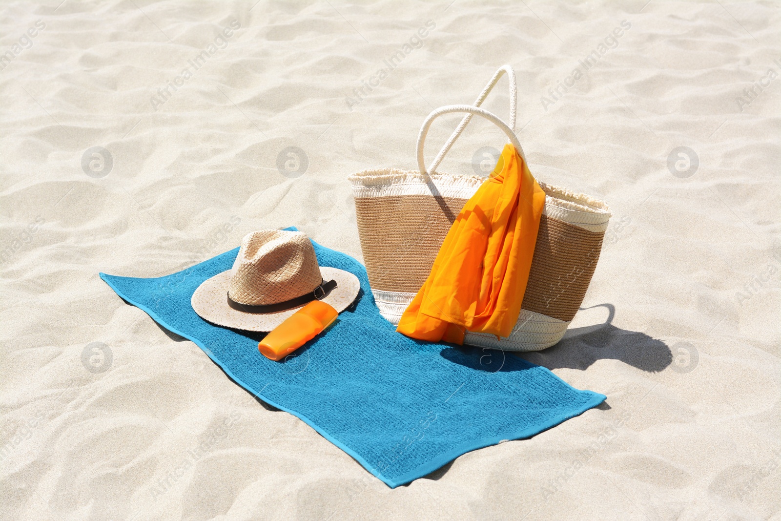 Photo of Blue towel, bag and accessories on sandy beach