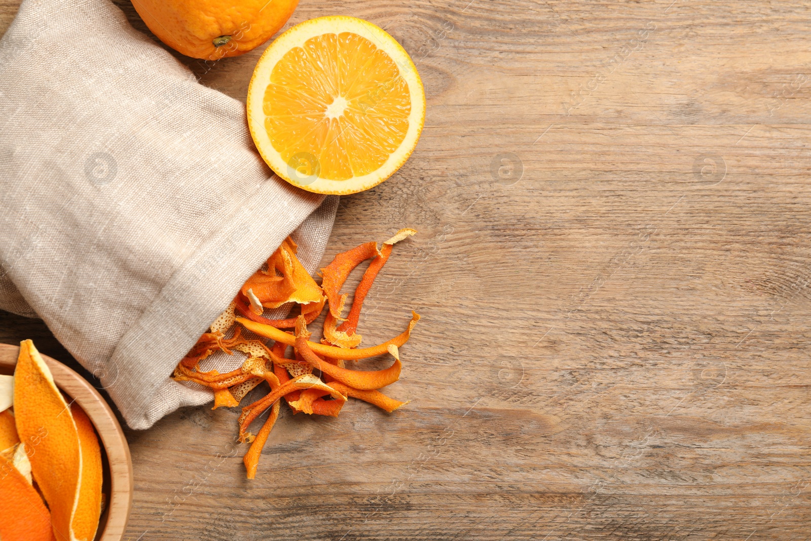 Photo of Dry orange peels and fresh fruit on wooden table, flat lay. Space for text