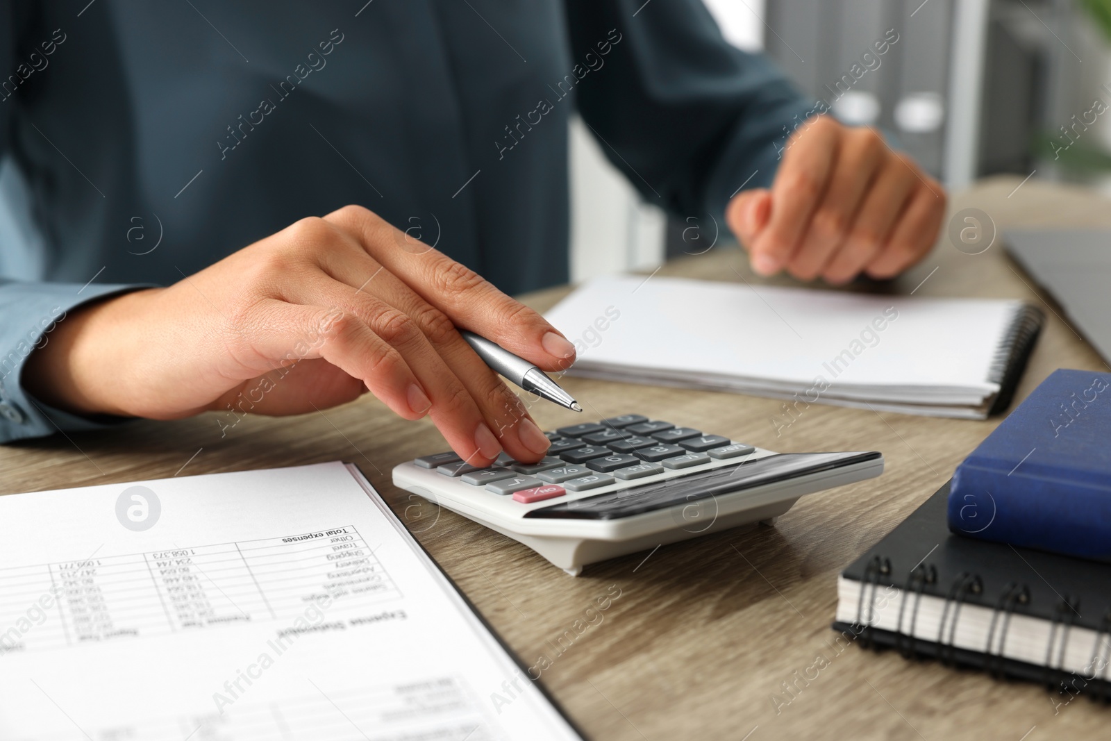 Photo of Woman using calculator at wooden table, closeup