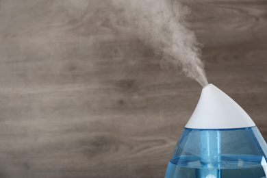 Photo of Modern air humidifier on wooden background, closeup. Space for text