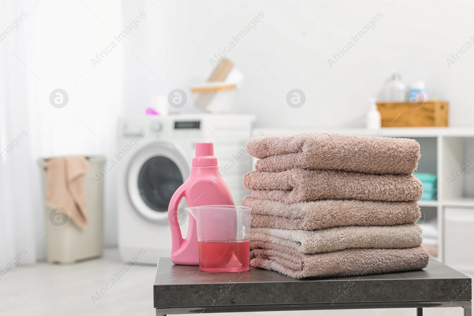 Photo of Stack of clean towels and liquid detergent on table in bathroom. Space for text