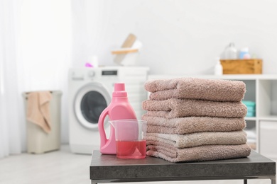 Stack of clean towels and liquid detergent on table in bathroom. Space for text