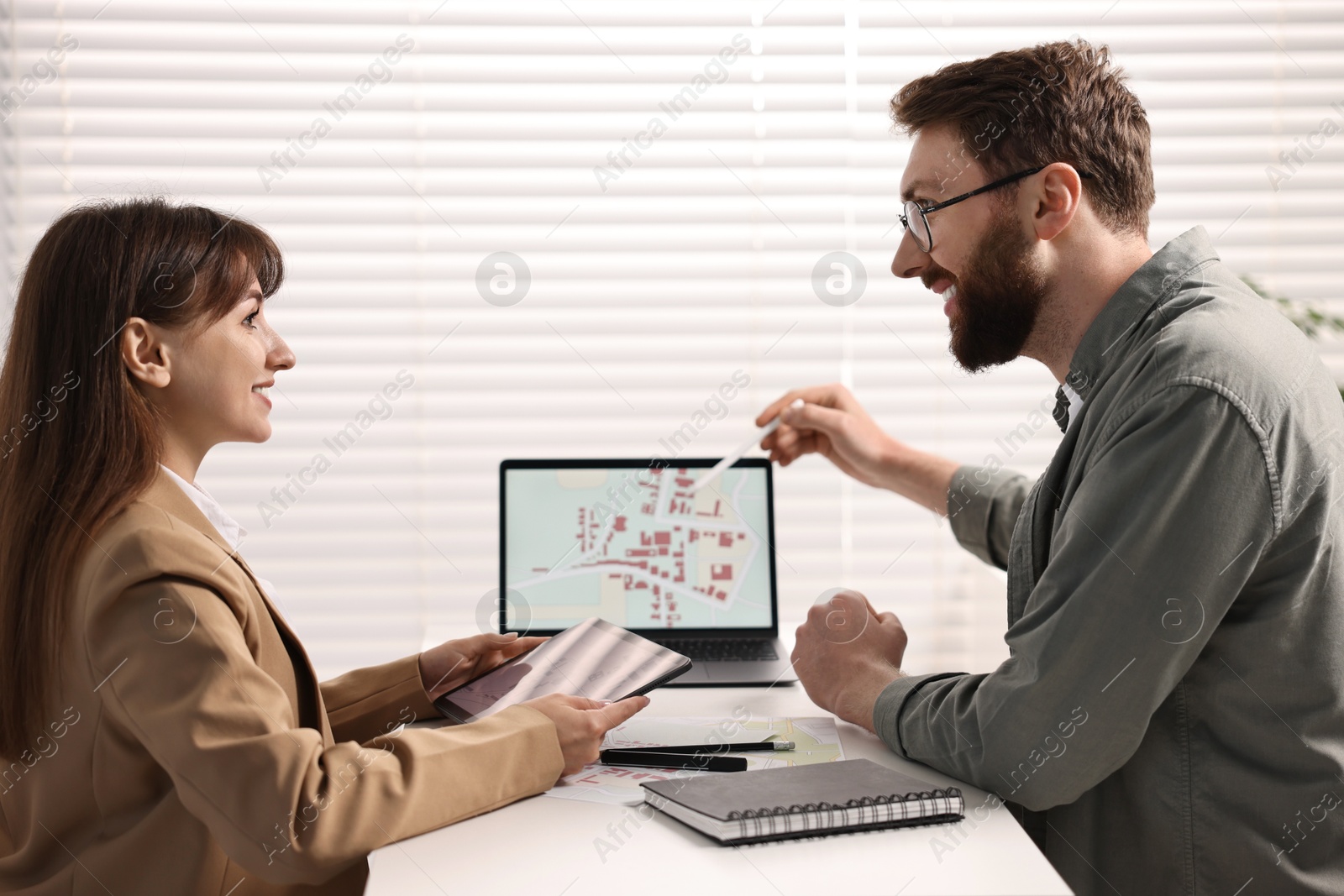 Photo of Cartographers working with cadastral map on computer at table in office