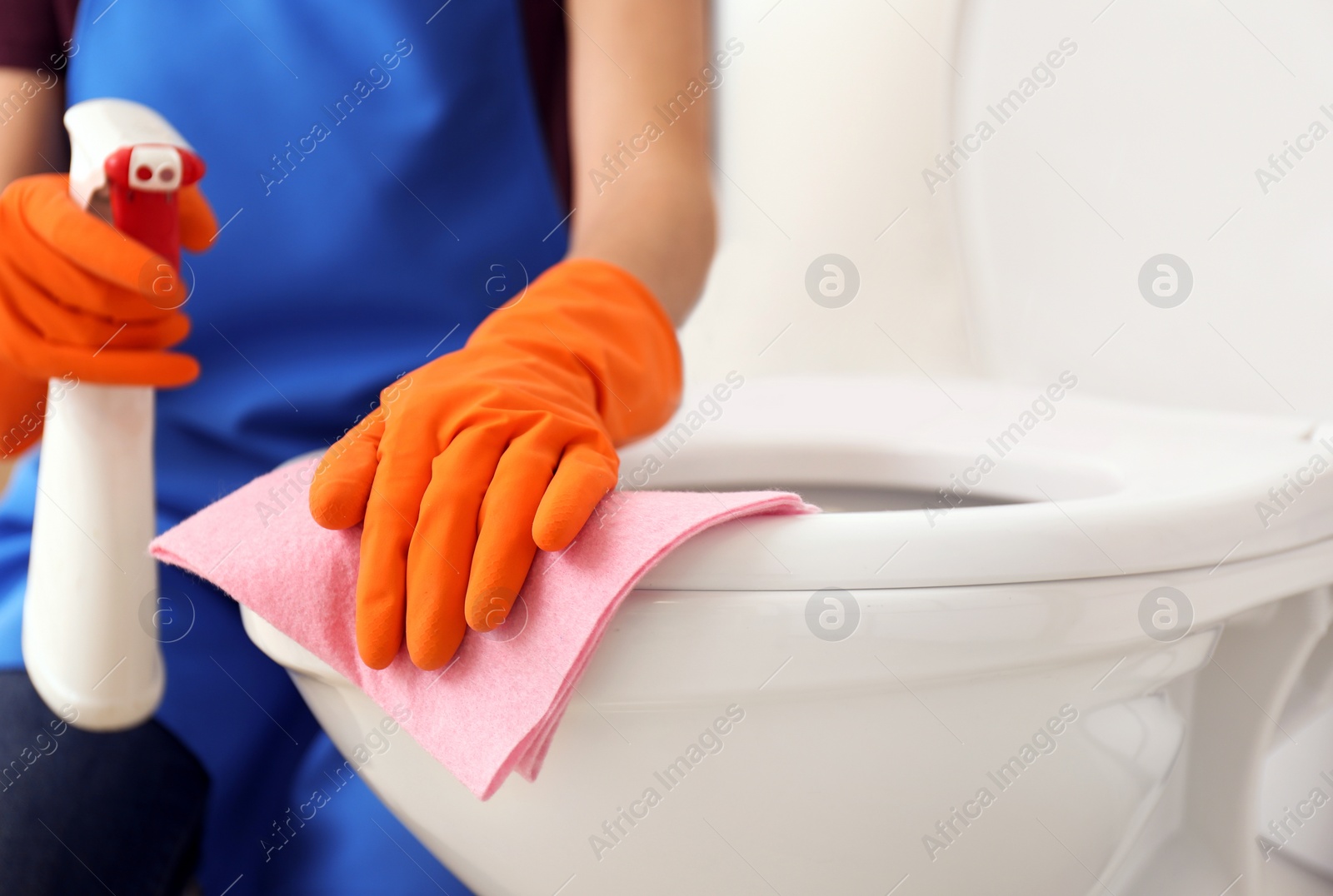 Photo of Woman cleaning toilet bowl in bathroom, closeup