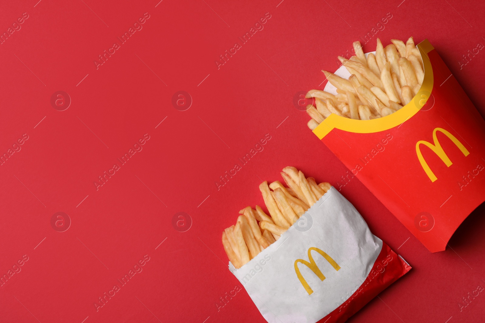 Photo of MYKOLAIV, UKRAINE - AUGUST 12, 2021: Small and big portions of McDonald's French fries on red background, flat lay. Space for text