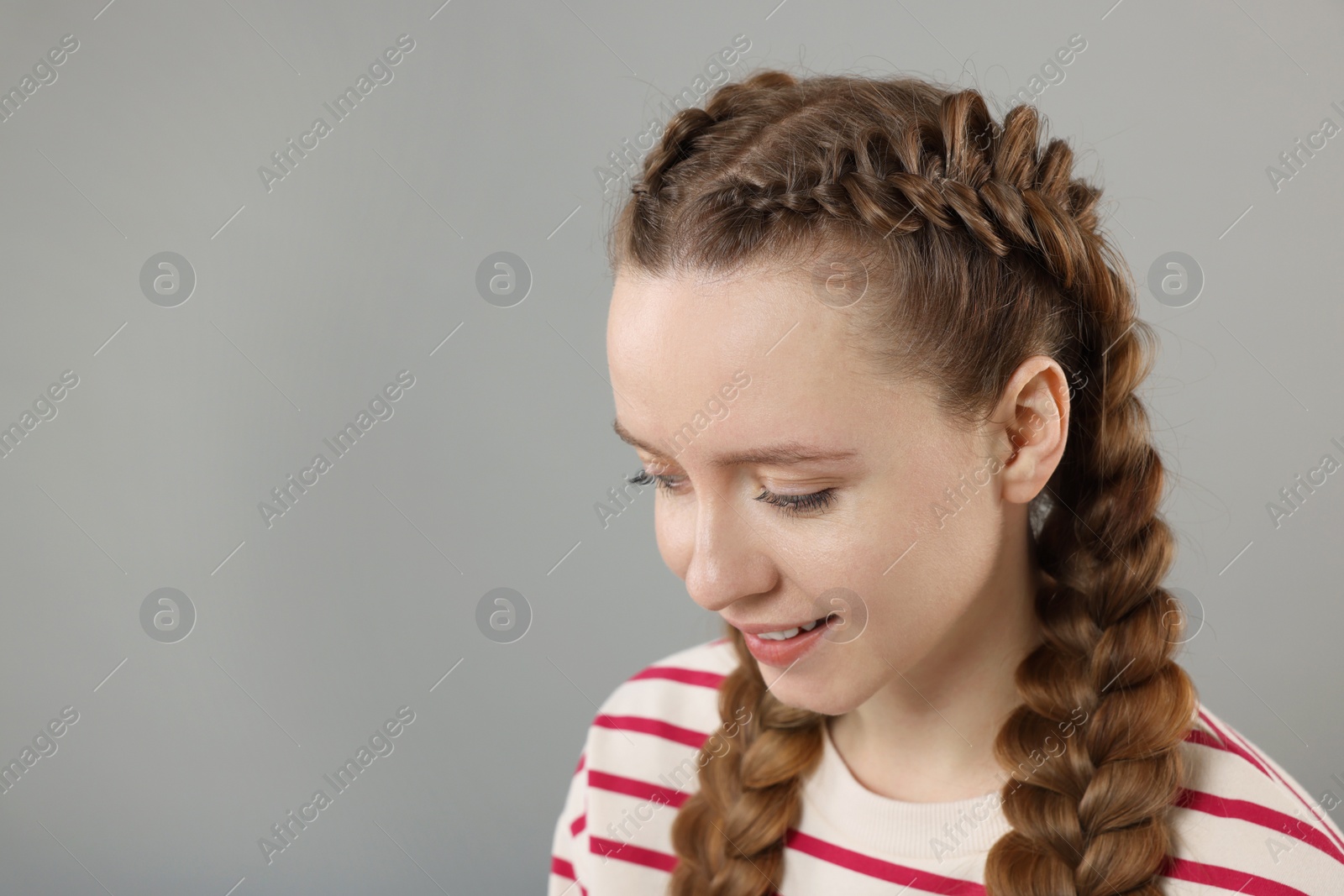 Photo of Woman with braided hair on grey background, space for text