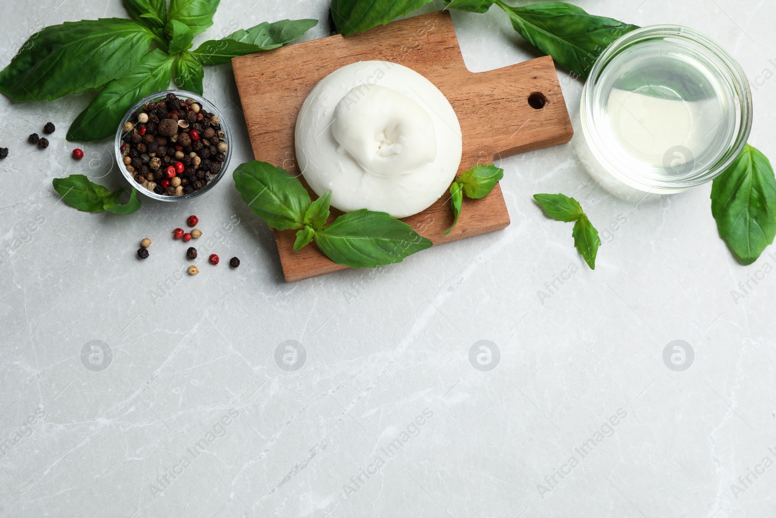 Photo of Delicious burrata cheese with basil and spices on light table, flat lay. Space for text