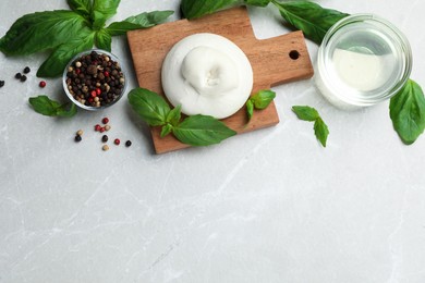 Photo of Delicious burrata cheese with basil and spices on light table, flat lay. Space for text