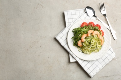 Photo of Delicious zucchini pasta with shrimps, cherry tomatoes and arugula served on light table, flat lay. Space for text
