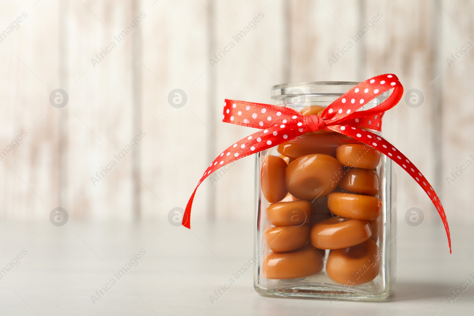 Photo of Sweet candies in jar on light grey table. Space for text