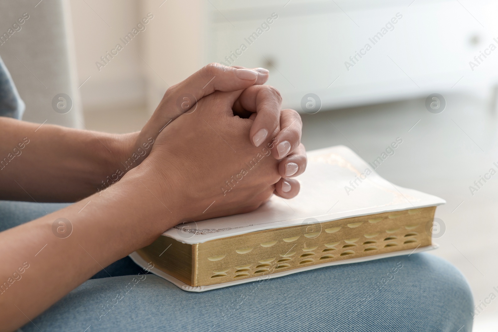 Photo of Religious woman with Bible praying indoors, closeup