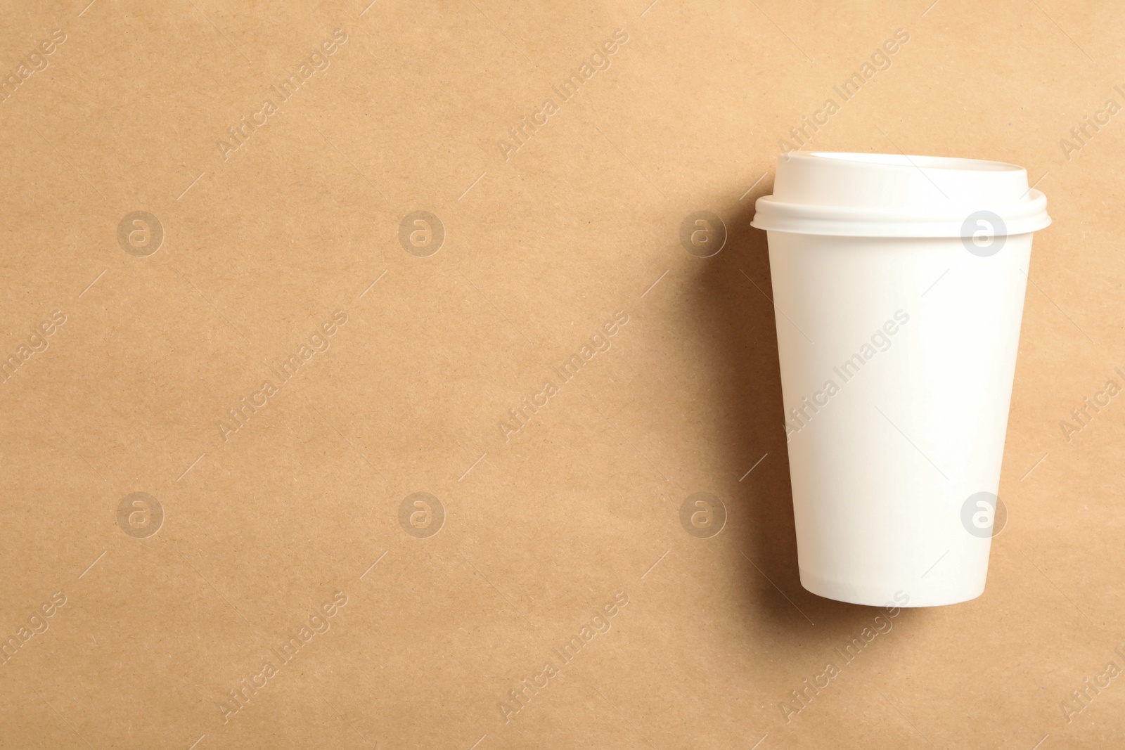 Photo of Takeaway paper coffee cup on beige background, top view. Space for text